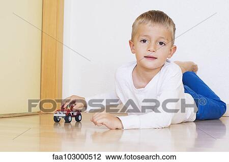 Boy lying on floor playing with toy truck View Large Photo Image Stock Image - Boy lying on floor playing with toy truck. Fotosearch