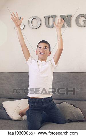 Boy playing on sofa with arms raised in the air View Large Photo Image Stock Photo - Boy playing on sofa with arms raised in the air. Fotosearch