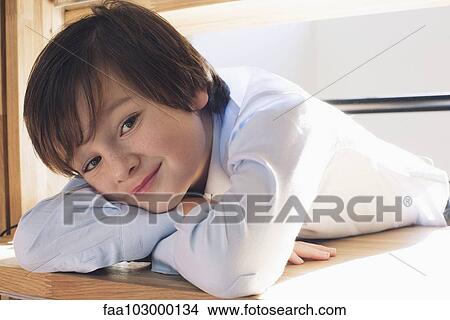 "Boy resting head on arms, smiling, portrait" View Large Photo Image Picture - "Boy resting head on arms, smiling, portrait". Fotosearch