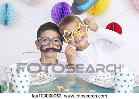 Stock Image - Boys wearing funny disguises at birthday party. Fotosearch