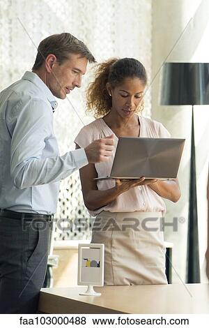 Stock Photo - Business associates looking at laptop computer together. Fotosearch