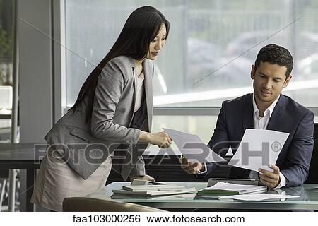 Stock Photograph - Business associates reviewing documents. Fotosearch