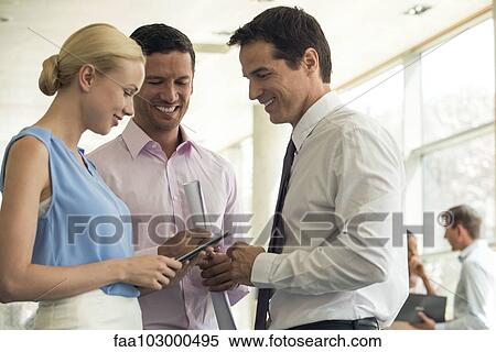 Stock Photography - Business colleagues conversing and using digital tablet. Fotosearch