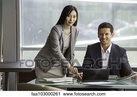Stock Image - Business professionals collaborating closely on project. Fotosearch