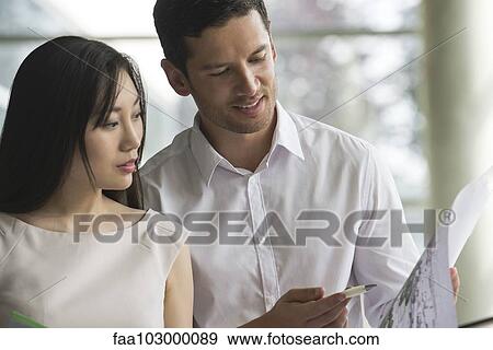 Stock Photo - Business professionals cooperating on project. Fotosearch
