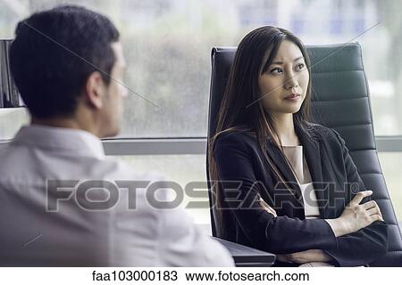 Stock Image - Business woman with arms folded looking away with air of disappointment. Fotosearch