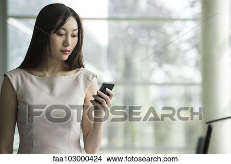 Picture - Businesswoman using smartphone. Fotosearch
