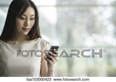 Stock Image - Businesswoman using smartphone. Fotosearch