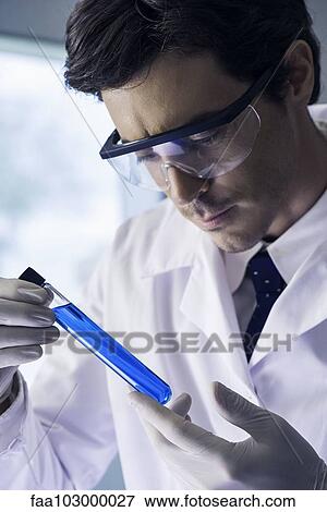 Chemist examing test tube containing blue liquid in laboratory View Large Photo Image Stock Photo - Chemist examing test tube containing blue liquid in laboratory. Fotosearch