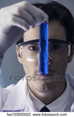 Chemist scrutinizing test tube containing blue liquid View Large Photo Image Stock Image - Chemist scrutinizing test tube containing blue liquid. Fotosearch