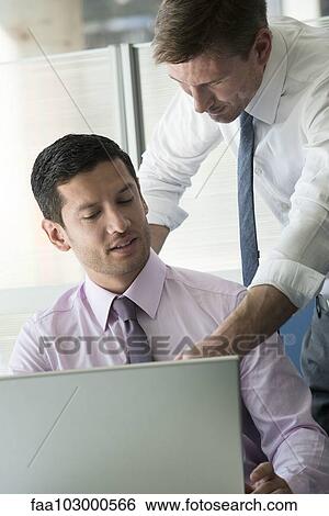 Stock Photograph - Colleagues collaborating on project. Fotosearch