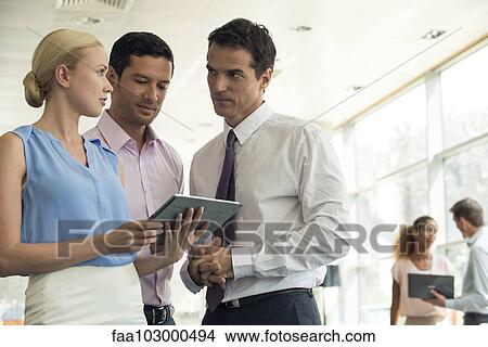 Colleagues looking at digital tablet together View Large Photo Image Picture - Colleagues looking at digital tablet together. Fotosearch