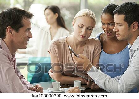 Stock Image - Colleagues looking at smartphone during coffee break. Fotosearch