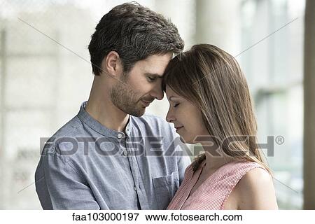 Stock Photo - "Couple touching foreheads, side view". Fotosearch