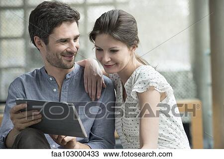 Couple using digital tablet together at home View Large Photo Image Stock Image - Couple using digital tablet together at home. Fotosearch