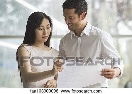Designers reviewing blueprint together View Large Photo Image Stock Photograph - Designers reviewing blueprint together. Fotosearch