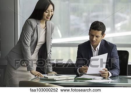 Executive reviewing document with assistant View Large Photo Image Stock Image - Executive reviewing document with assistant. Fotosearch