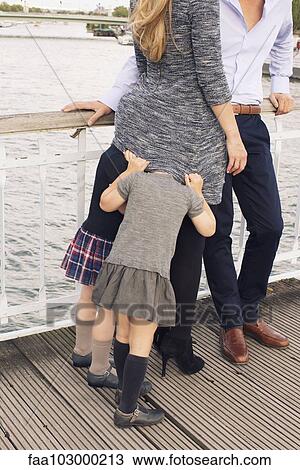"Family together outdoors, little girls hiding under mother's sweater" View Large Photo Image Stock Image - "Family together outdoors, little girls hiding under mother's sweater". Fotosearch