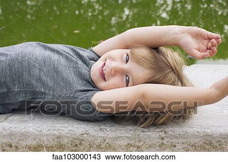 "Little girl lying beside pond, smiling, portrait" View Large Photo Image Stock Image - "Little girl lying beside pond, smiling, portrait". Fotosearch