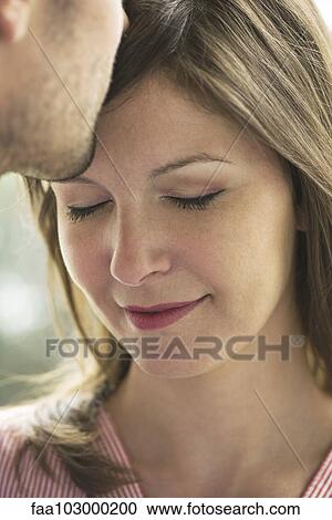 Stock Image - "Man kissing woman's forehead, cropped". Fotosearch