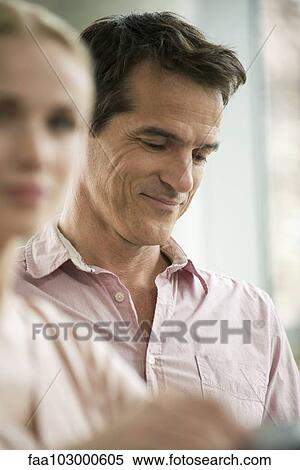 Stock Photography - "Man looking down in thought, smiling". Fotosearch