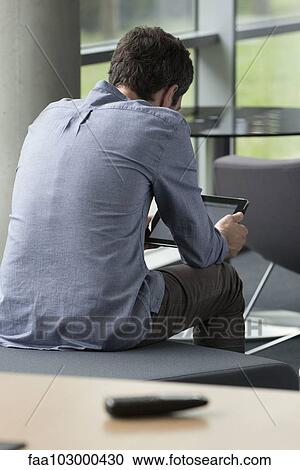 "Man using digital tablet alone at home, rear view" View Large Photo Image Stock Image - "Man using digital tablet alone at home, rear view". Fotosearch