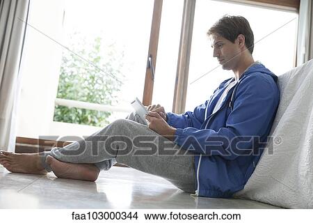 Man using digital tablet at home View Large Photo Image Picture - Man using digital tablet at home. Fotosearch
