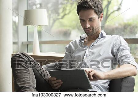 Man using digital tablet at home View Large Photo Image Stock Photo - Man using digital tablet at home. Fotosearch