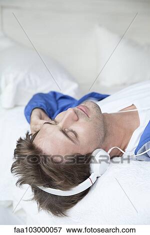 Stock Photo - Man wearing headphones lying on back. Fotosearch
