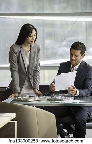 Manager reviewing document with assistant View Large Photo Image Stock Photo - Manager reviewing document with assistant. Fotosearch