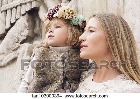 "Mother and young daughter together outdoors, looking away attentively" View Large Photo Image Picture - "Mother and young daughter together outdoors, looking away attentively". Fotosearch