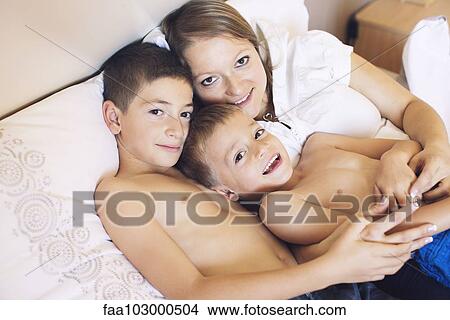 "Mother and young sons relaxing together on bed, portrait" View Large Photo Image Picture - "Mother and young sons relaxing together on bed, portrait". Fotosearch