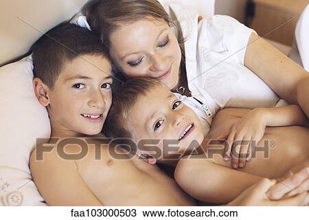 "Mother and young sons relaxing together on bed, portrait" View Large Photo Image Stock Image - "Mother and young sons relaxing together on bed, portrait". Fotosearch