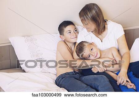 Mother and young sons relaxing together on bed View Large Photo Image Stock Photo - Mother and young sons relaxing together on bed. Fotosearch