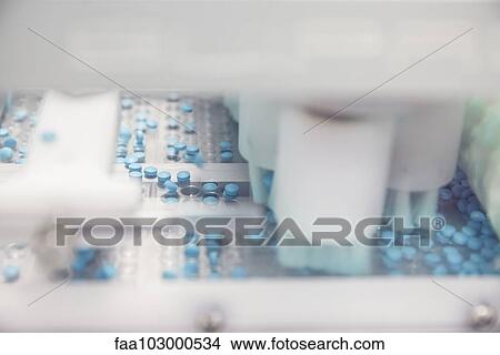 Pills dropping onto plastic trays in blisterpack sealing machine View Large Photo Image Picture - Pills dropping onto plastic trays in blisterpack sealing machine. Fotosearch