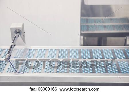Stock Photograph - Pills on conveyor belt entering blisterpack sealing machine. Fotosearch