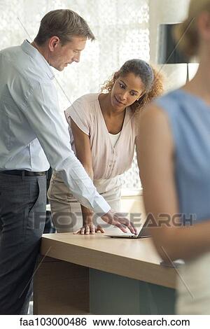 Stock Photograph - Salesman demonstrating laptop computer for customer. Fotosearch
