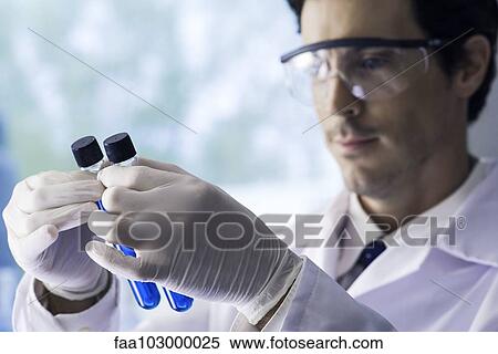 Scientist scrutinizing test tubes containing blue liquid in lab View Large Photo Image Stock Photography - Scientist scrutinizing test tubes containing blue liquid in lab. Fotosearch