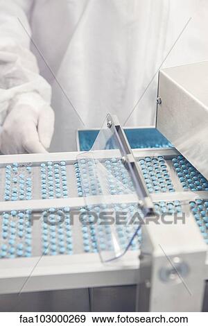 Stock Photo - Technician monitoring prescription drug packaging process. Fotosearch
