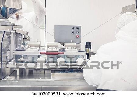 Stock Image - Technicians at work in prescription drug production facility. Fotosearch