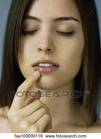 Stock Photograph - "Teenage girl touching lip, eyes closed, portrait". Fotosearch