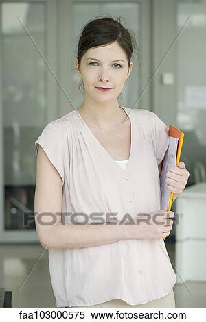 "Woman carrying folders, smiling, portrait" View Large Photo Image Stock Photography - "Woman carrying folders, smiling, portrait". Fotosearch