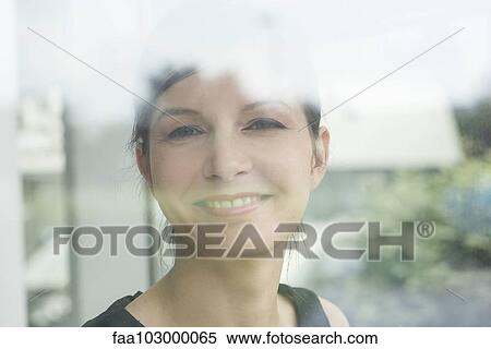 "Woman looking through window, smiling, portrait" View Large Photo Image Stock Photography - "Woman looking through window, smiling, portrait". Fotosearch