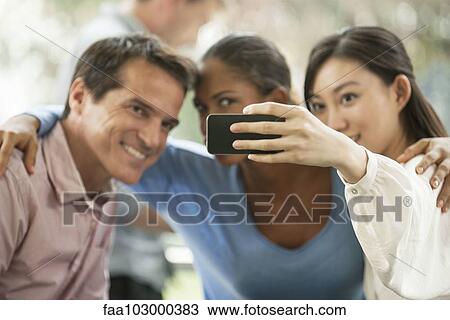 Woman photographing herself and friends with smartphone View Large Photo Image Stock Image - Woman photographing herself and friends with smartphone. Fotosearch