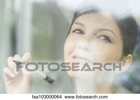 Picture - Woman preparing to write on window with marker. Fotosearch