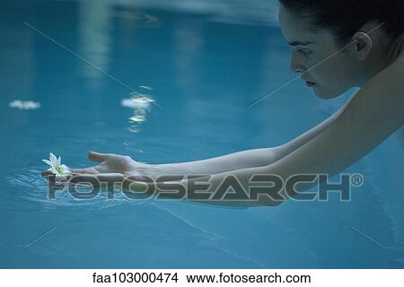 Woman reaching for flower floating in pool View Large Photo Image Picture - Woman reaching for flower floating in pool. Fotosearch
