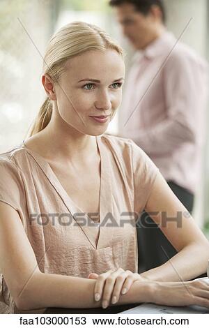 Stock Image - "Woman sitting at cafe table, smiling". Fotosearch