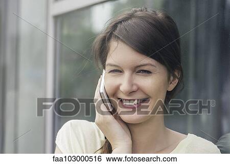 Stock Photograph - "Woman using cell phone, smiling cheerfully". Fotosearch