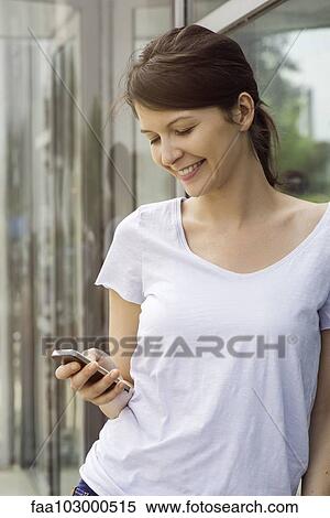 "Woman using smartphone outdoors, smiling" View Large Photo Image Stock Photography - "Woman using smartphone outdoors, smiling". Fotosearch