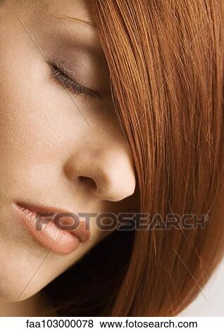 Stock Photo - Woman's face and red hair covering one eye. Fotosearch